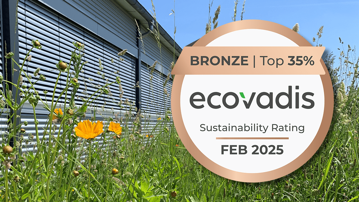 Blumenwiese mit Bronze Medaille 2024 Eine EcoVadis Bronze-Medaille für das Jahr 2025 schwebt vor einer saftig grünen Blumenwiese.