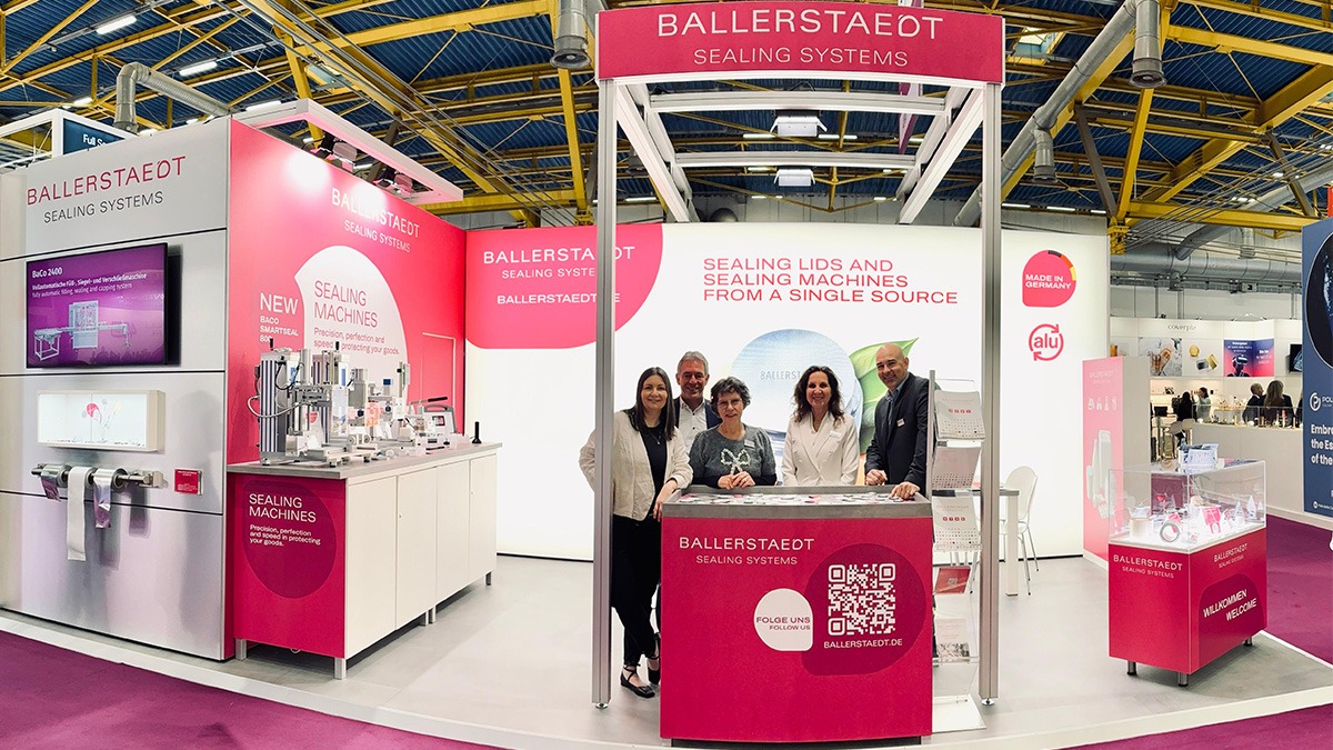Ein Messestand in kräftigem Magenta. Mittig steht das Messeteam mit 5 Personen.
